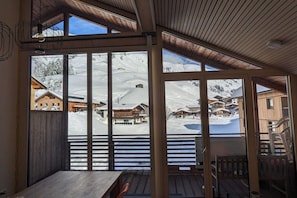 Eine Holzterrasse mit Blick auf ein verschneites Bergdorf.