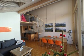 Un intérieur moderne comprenant un coin repas, un canapé, un escalier et une cuisine.