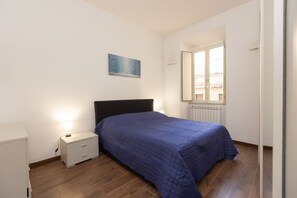 A bedroom with a bed, bedside table, and a window with a view. - A spacious and bright 87-square-meter apartment perfect for six people, located on the first floor of a building (equipped with an elevator, though there are a few steps to reach it; NOT suitable for people with disabilities).The property is centrally lo (Rome)
