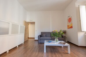 A modern living room with a grey sofa, a white coffee table with books and flowers, and a bookshelf. - A spacious and bright 87-square-meter apartment perfect for six people, located on the first floor of a building (equipped with an elevator, though there are a few steps to reach it; NOT suitable for people with disabilities).The property is centrally lo (Rome)