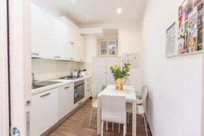 A compact kitchen with white cabinets, a dining table with chairs, and a small window above the door. - A spacious and bright 87-square-meter apartment perfect for six people, located on the first floor of a building (equipped with an elevator, though there are a few steps to reach it; NOT suitable for people with disabilities).The property is centrally lo (Rome)