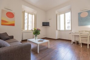 A modern living room with a sofa, coffee table, TV, and a view through the windows. - A spacious and bright 87-square-meter apartment perfect for six people, located on the first floor of a building (equipped with an elevator, though there are a few steps to reach it; NOT suitable for people with disabilities).The property is centrally lo (Rome)