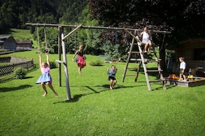 A playground with a wooden climbing structure and swings. - in the Bergquell house with horse stable (Au, Bregenzerwald)