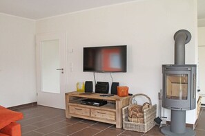 A living room with a television, a wooden entertainment unit, a fireplace, and a door. - Holiday home with 5 bedrooms (Röbel an der Müritz)