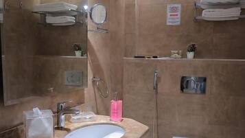 Een badkamer met een wastafel, spiegel, handdoekhouder en douche.