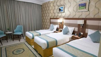 A hotel room with two beds, a small table, a chair, and a decorative rug.