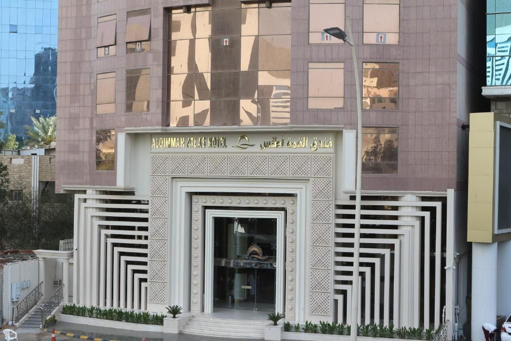A hotel entrance with a modern design, featuring a central doorway flanked by symmetrical patterns and a sign above.