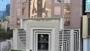 A hotel entrance with a modern design, featuring a central doorway flanked by symmetrical patterns and a sign above.