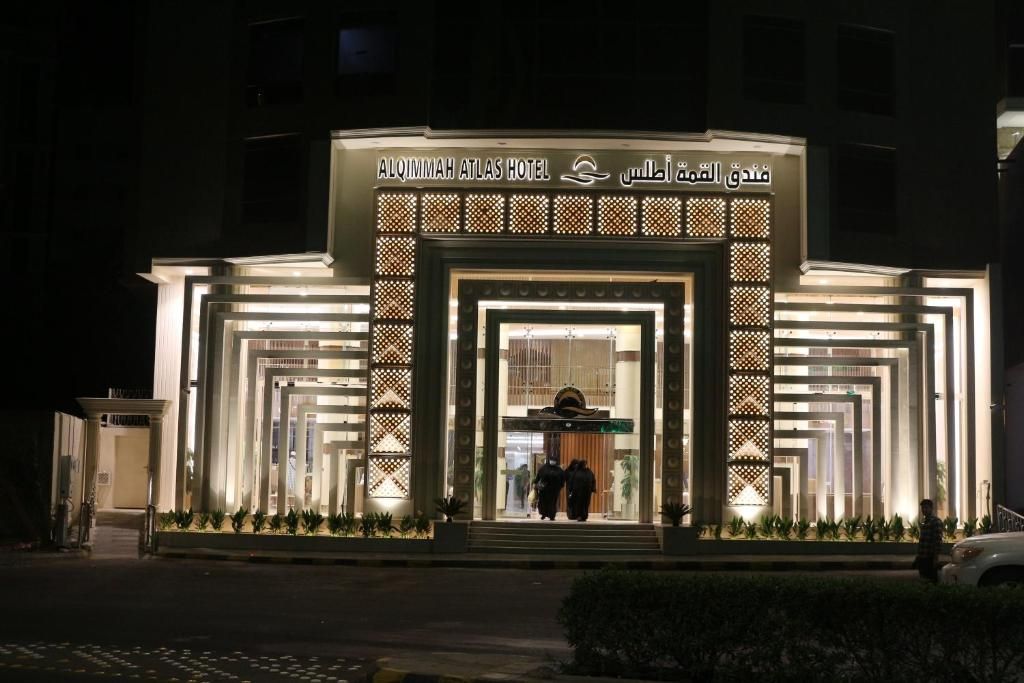 The exterior of AlQimmah Atlas Hotel with a modern facade and illuminated entrance.