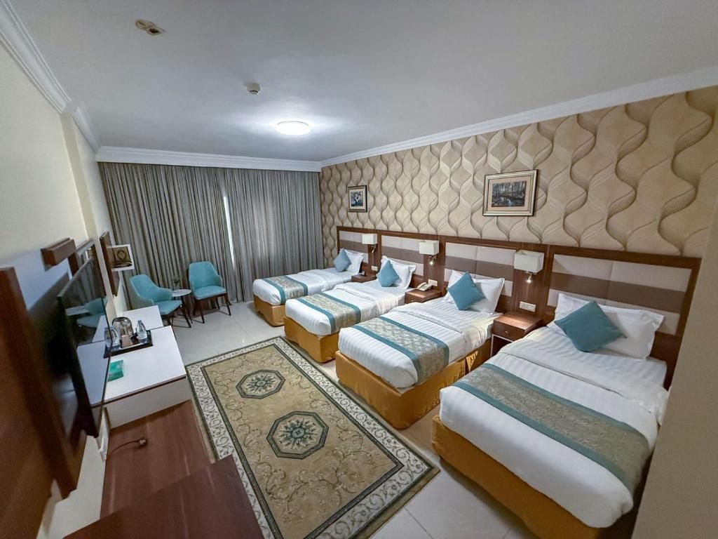 Een hotelkamer met vier bedden, een bureau, een stoel en een televisietoestel.