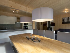 Eine moderne Küche mit Holzschränken, einem Esstisch mit Stühlen und Pendelleuchten.