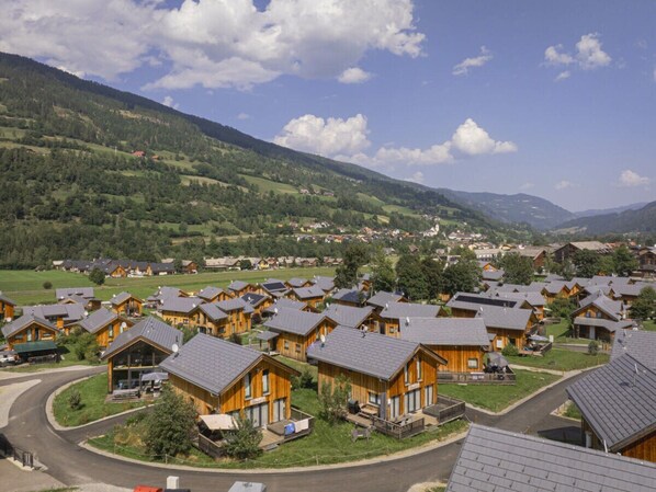 A cluster of wooden cabins with sloped roofs, surrounded by green hills and a clear sky. - One-bedroom Cabin (Sankt Georgen am Kreischberg)