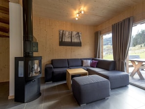 Un salon moderne avec un canapé d’angle, une petite table en bois et une cheminée noire.