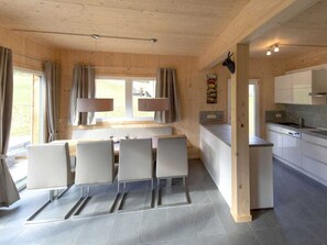Une cuisine moderne avec un coin repas, un plafond en bois et une vue par la fenêtre.