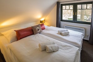 A hotel room with two beds, a window with curtains, and a wall-mounted light fixture. - Holiday home with 2 bedrooms (Nossentiner Hütte OT Drewitz)