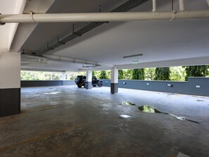 Un aparcament amb sòls de formigó, columnes i un vehicle estacionat.