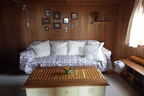 A cozy room with a wooden wall, a patterned sofa, a small table with a vase, and a bench. - Holiday home with 4 bedrooms (Riefensberg)