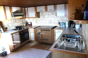 A kitchen with a stove, oven, microwave, and a sink with a dish rack. - Holiday home with 4 bedrooms (Riefensberg)