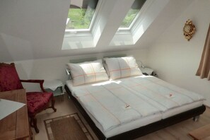 Un dormitorio con una cama, una silla, un escritorio y una ventana.
