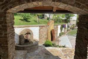 An arched stone structure with a circular well, surrounded by stone walls and a grassy area with plants. - Holiday apartment with 2 bedrooms (Stainz)