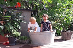 Two children standing in a large metal tub outdoors with potted plants around. - Apart Greber Bersbuch (Andelsbuch)