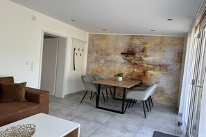 Un salon moderne comprenant un coin repas, un canapé, une table basse et un mur à texture.