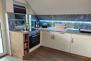 A modern kitchen with a built-in oven, a coffee maker, and a sink. - Holiday apartment with 1 bedroom (Blumenholz OT Weisdin)