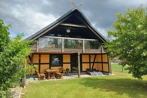A modern house with a sloped roof, large windows, and a patio with outdoor furniture. - Holiday apartment with 1 bedroom (Blumenholz OT Weisdin)