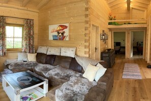 A cozy cabin interior with a sectional sofa, a coffee table, and a painting on the wall. - Nature Chalet Pitztal (Wenns)