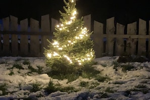 A snow-covered landscape with a lit Christmas tree in the foreground. - Nature Chalet Pitztal (Wenns)