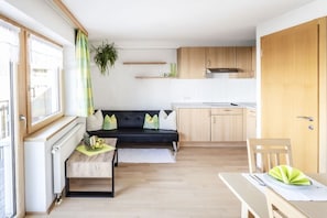 Um espaço compacto com sofá, mesa de jantar e cozinha compacta.