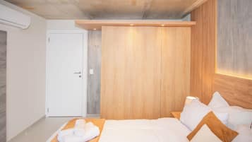 A modern bedroom with a large bed, a wooden wardrobe, and a ceiling light.
