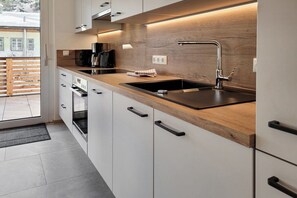 Een moderne keuken met een houten aanrecht, een roestvrijstalen spoelbak en witte keukenkastjes.