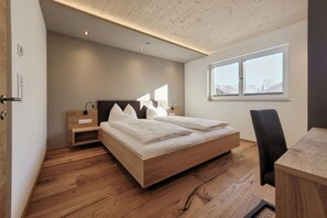 Ein Schlafzimmer mit einem hölzernen Bett, Nachttischen, einem Schreibtisch und einem Fenster mit Blick.