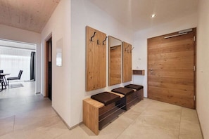 A modern bathroom with a wooden vanity, mirrors, and a large wooden door. - 80m² Guesthouse Sonne (Bichlbach)