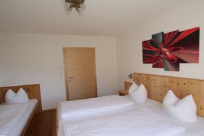 A hotel room with two beds, a wooden door, and a wall-mounted abstract art piece. - Apartment in Fügen with swimming pool (Fügen)