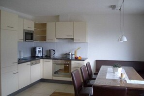 A modern kitchen with a dining area, featuring cabinets, a stove, and a table with chairs. - Apartment in Fügen with swimming pool (Fügen)