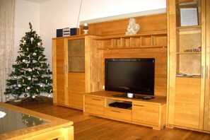 A living room with a wooden entertainment center, a television, and a Christmas tree. - Apartment in Fügen with swimming pool (Fügen)