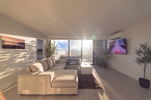 Een moderne woonkamer met een bank, een salontafel en een aan de muur bevestigde televisie.