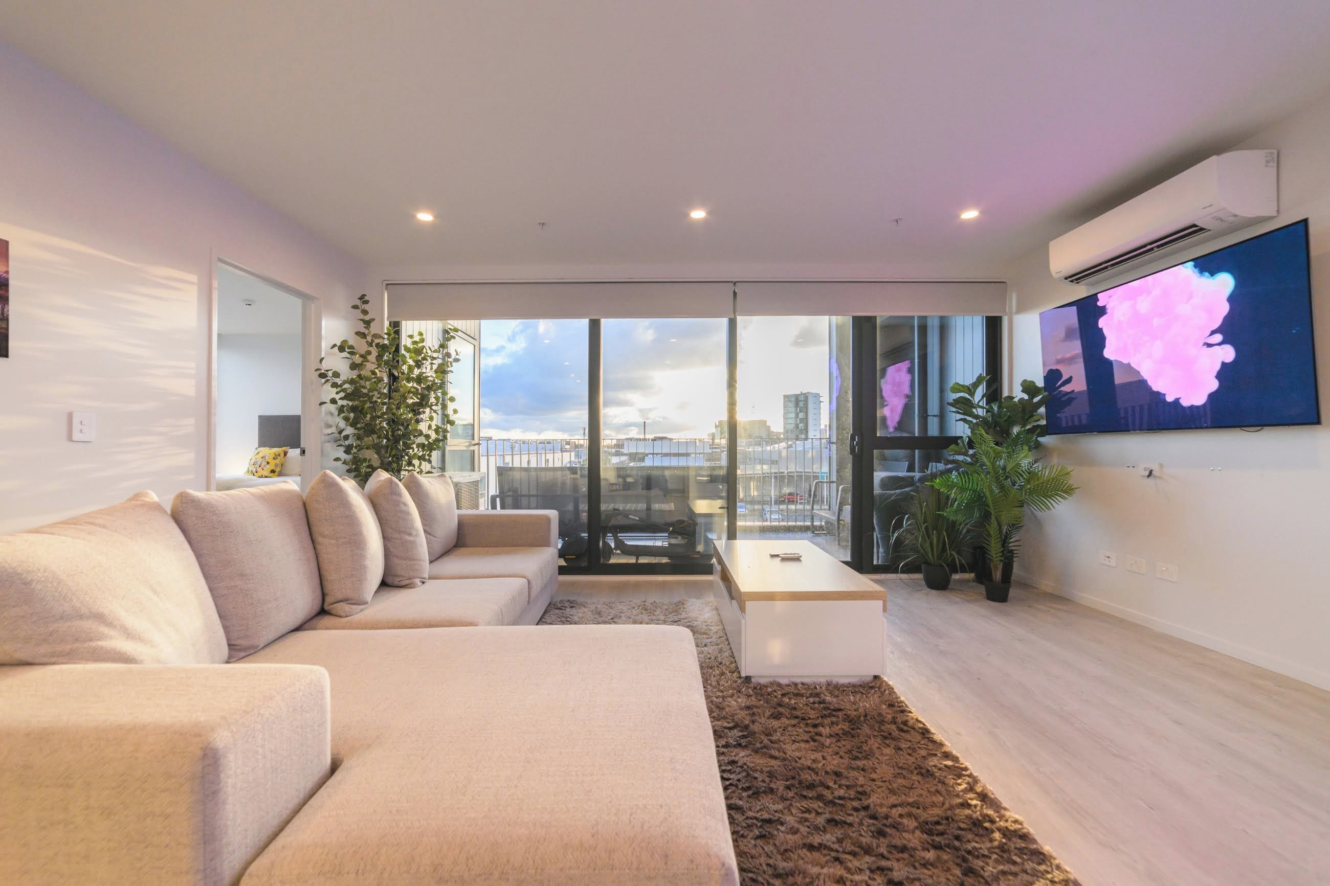 A modern living room with a sofa, coffee table, and potted plants.