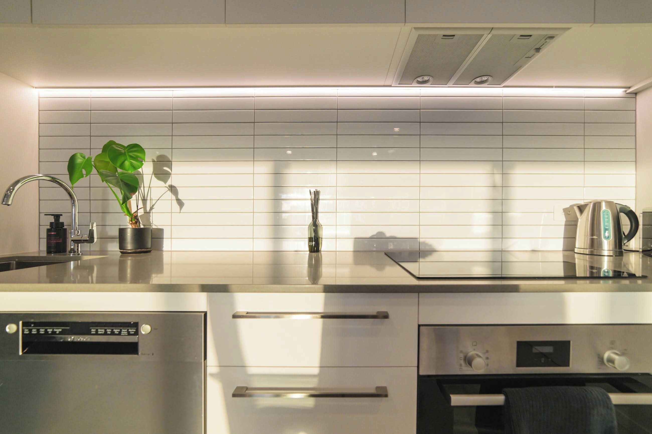 A modern kitchen with a stainless steel refrigerator, a built-in oven, and a kettle on the counter.
