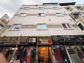 A multi-story building with various shops on the ground floor, including a silk bunkar and a textile store. - Shivala grand guest House Varanasi (Varanasi)