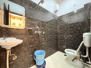 A bathroom with a sink, toilet, shower, and a blue bucket. - Shivala grand guest House Varanasi (Varanasi)