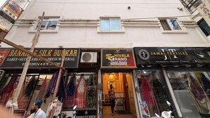 Un edificio de varios pisos con diversas tiendas en la planta baja, incluyendo una tienda de seda y una tienda de textiles.