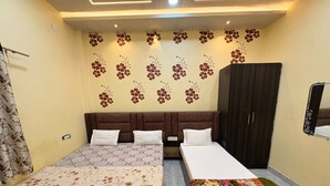 Una habitación con dos camas, un armario y una pared con diseños florales.