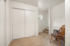 A hallway with a carpeted floor, a wooden chair, a white door, and a window with a view of greenery outside. - Kanarraville Home - Near Zion & Kanarra Falls (Cedar City)