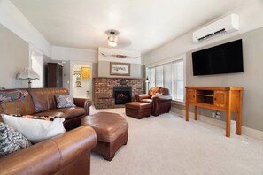 A living room with a fireplace, leather sofas, a television, and a wooden side table. - Kanarraville Home - Near Zion & Kanarra Falls (Cedar City)