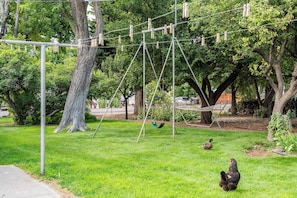 Ein Park mit einer Schaukel, einer Hängematte und einer Rasenfläche mit Bäumen.