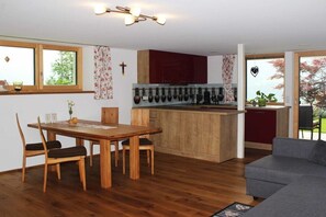 Eine moderne Küche mit Holzausstattung, einem Esstisch mit Stühlen und einem grauen Sofa.
