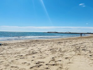 A beach with footprints in the sand, a pier in the distance, and a clear sky. - Elegant Coastal Apartment with Marina & Beach View (Port Saplaya)